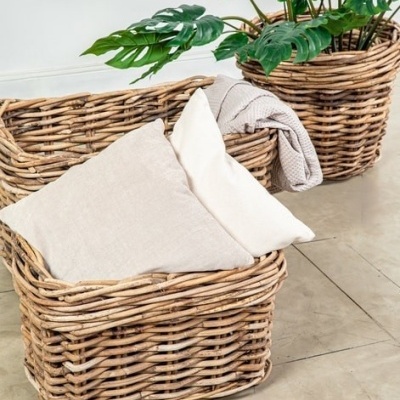 Cestos de vime com almofadas e manta ao lado de planta verde