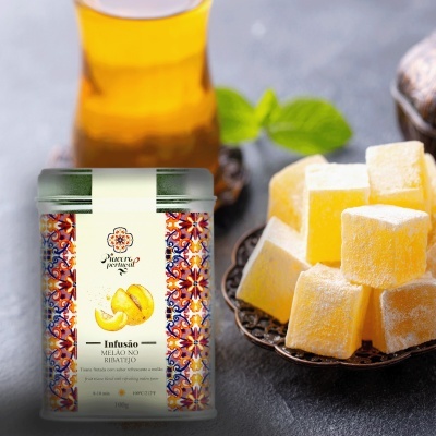 Frasco de infusão de chá ao lado de um prato com pedaços de doce amarelo