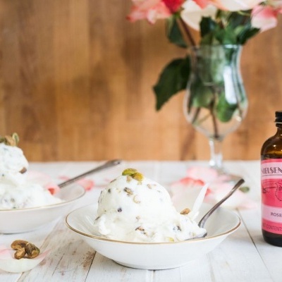 Dois pratos com gelado branco e frasco de água de rosas ao lado sobre mesa branca