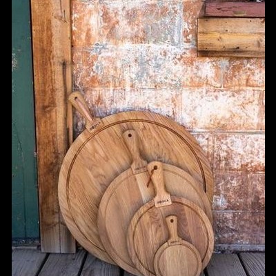 Tábuas de madeira redondas com alças encostadas numa parede de tijolo