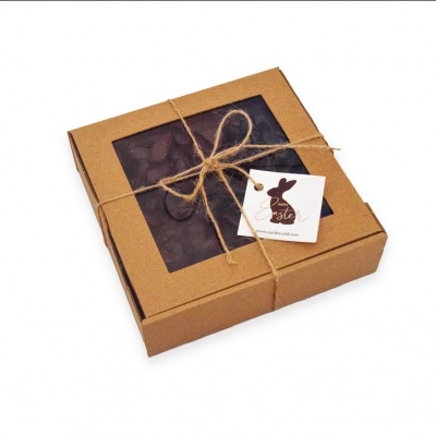 Caixa de bombons de chocolate com tampa transparente e etiqueta com coelho.