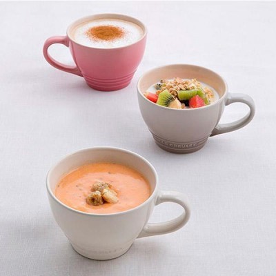 Três chávenas de cerâmica com cappuccino, salada de frutas e sopa cremosa.