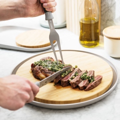 Carne sendo cortada numa tábua de madeira na cozinha