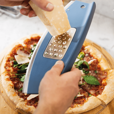 Ralador manual azul a ralar queijo sobre pizza numa tábua