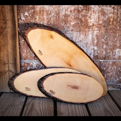 Três tábuas de madeira rústica com casca nas bordas sobre chão de madeira