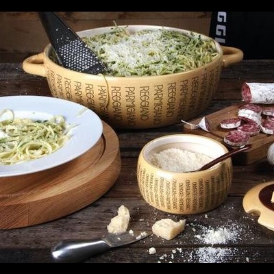 Taças amarelas com esparguete e queijo, enchidos, alho e queijo numa mesa de madeira.