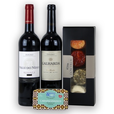 Duas garrafas de vinho tinto, caixa preta de queijos e lata decorativa com texto CARAPAUZINHOS.