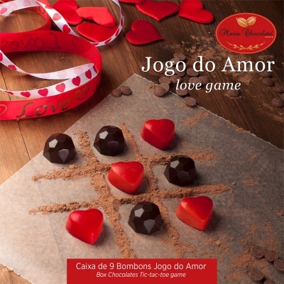 Caixa de bombons 'Jogo do Amor' com bombons em forma de coração e decoração de fita vermelha e branca