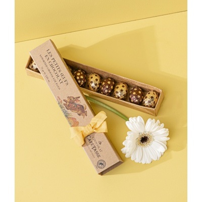 Caixa de presente com ovos de chocolate e flor branca em fundo amarelo