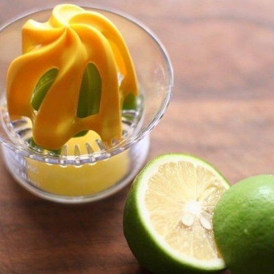 Espremedor de citrinos amarelo e transparente com limão cortado ao meio