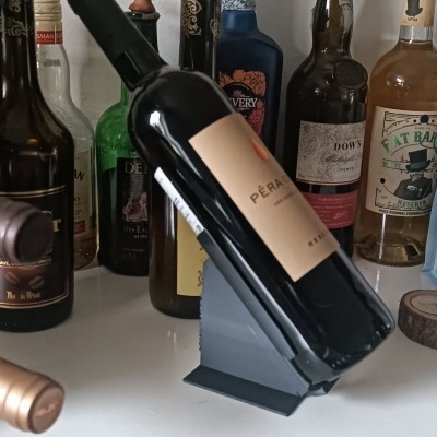 Garrafas de bebidas alcoólicas numa bancada, com destaque para garrafa de vinho em suporte