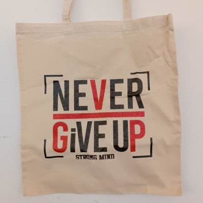 Saco de tecido bege com texto motivacional em preto e vermelho