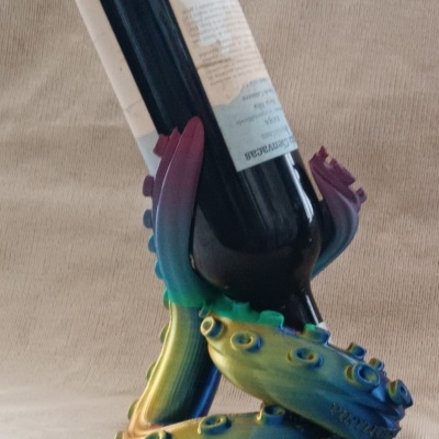 Suporte para garrafa colorido com tentáculos segurando uma garrafa de vinho preta