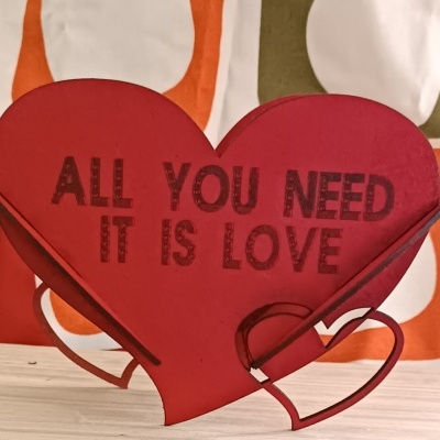 Suporte decorativo em forma de coração vermelho com texto em preto