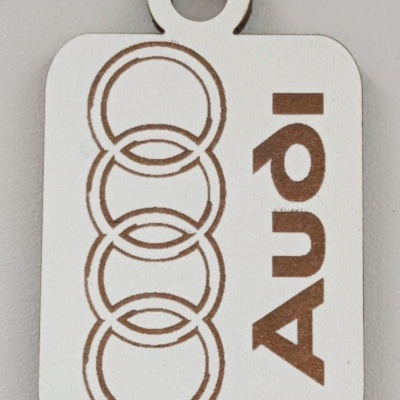 Pingente branco com quatro círculos entrelaçados e logo Audi em castanho