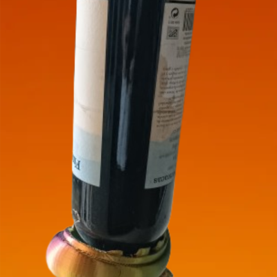 Garrafa de vidro escuro em suporte dourado com fundo laranja