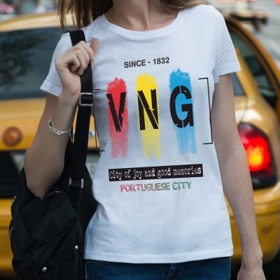 T-shirt branca com estampado colorido e texto, usada por pessoa com mochila preta em frente a carro amarelo