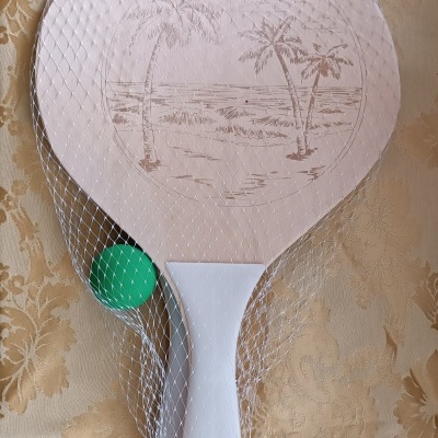 Conjunto de raquete de paddle de madeira clara com desenho de palmeiras e bola verde em rede branca