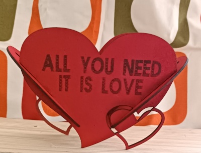 Suporte decorativo em forma de coração vermelho com texto em preto