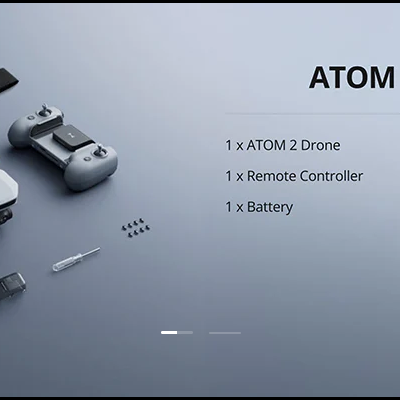 Kit completo de drone ATOM 2 com drone cinzento, comando, bateria e acessórios sobre superfície cinzenta.