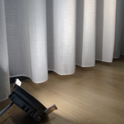 Luz de embutir preta no chão de madeira junto a cortina branca