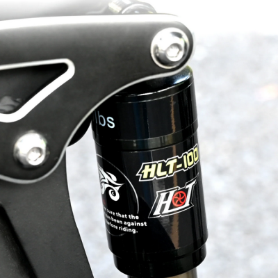 Suspensão traseira para bicicleta com etiquetas HLT-100 e HOT, montada em estrutura metálica preta.