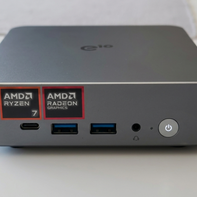 Mini PC cinzento com etiquetas AMD Ryzen 7 e Radeon Graphics, portas USB e botão de ligar