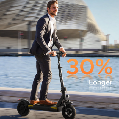 Homem com fato numa trotinetepreta junto à água e edifício moderno