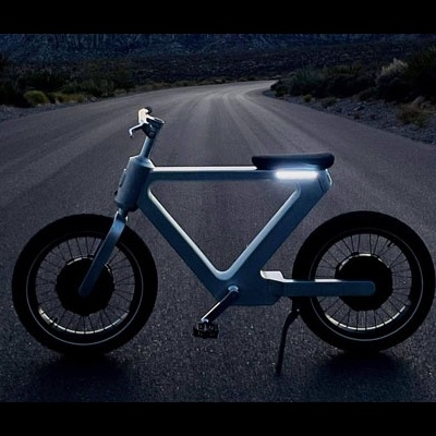 bicicleta elétrica azul claro numa estrada à noite com luz frontal ligada