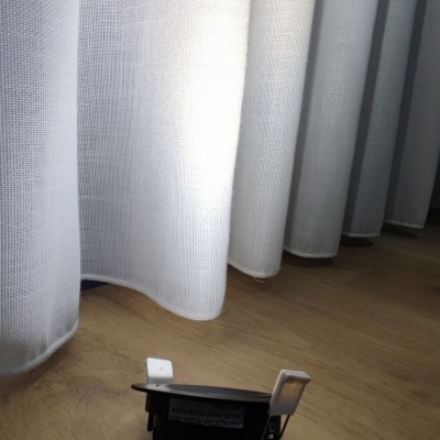 Luz embutida preta redonda junto a cortinas brancas numa sala