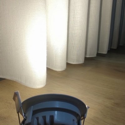 Lâmpada embutida branca em pavimento de madeira junto a cortinas brancas