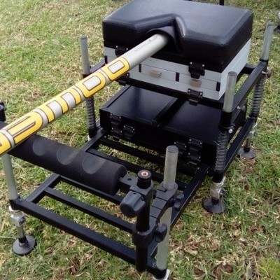 Equipamento de pesca com almofada preta e suporte de cana branco e amarelo em relva