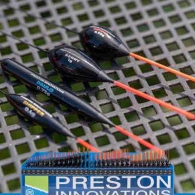 Flutuadores de pesca Preston Innovations em caixa azul sobre superfície metálica perfurada.