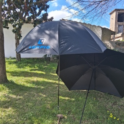 Dois guarda-chuvas pretos abertos no exterior, um com texto 'SCORPIO' azul e branco.