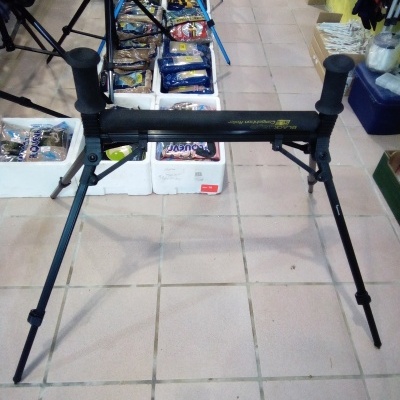 Aparelho tripé de apoio para pesca preto com punhos de borracha sobre pavimento cerâmico em loja