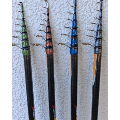 Quatro canas de pesca telescópicas coloridas contra parede branca.