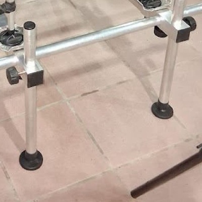 Estrutura metálica prateada com pés em plástico preto sobre piso de ladrilhos bege