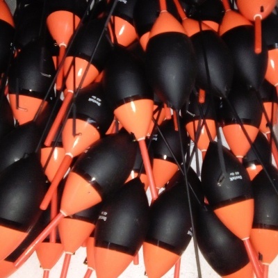 Bóias de pesca pretas e laranja numa caixa de poliestireno