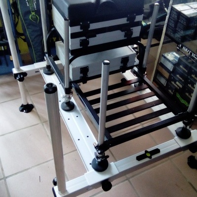 Estrutura metálica branca com assento almofadado preto e caixas organizadoras sobre tijoleira.