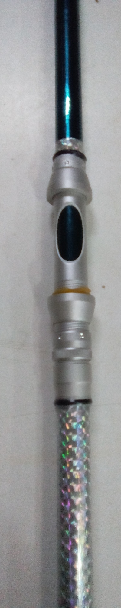 Punho e parte do cabo de uma cana de pesca com detalhes prateados e holográficos