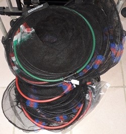 Redes de pesca circulares com armações coloridas empilhadas no chão