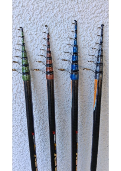 Quatro canas de pesca telescópicas coloridas contra parede branca.