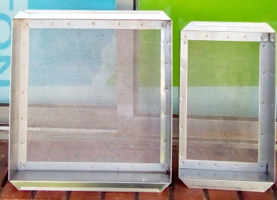 Duas caixas metálicas perfuradas de diferentes tamanhos, com estrutura prateada e fundo de malha.