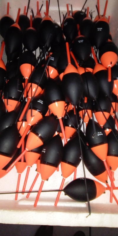 Bóias de pesca pretas e laranja numa caixa de poliestireno