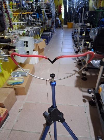 Suporte com tripé azul e estrutura metálica vermelha numa loja de acessórios