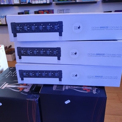 Caixas brancas de ventiladores Ocean Breeze empilhadas sobre caixas negras numa loja