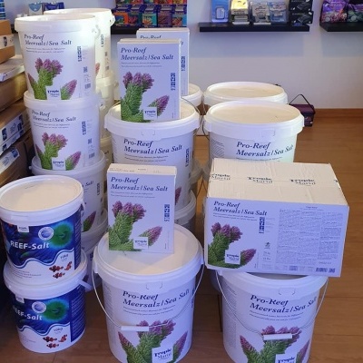 Recipientes e caixas de sal marinho para aquários empilhados em loja com chão de madeira
