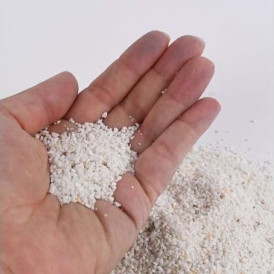 Mão segurando grânulos brancos sobre fundo branco