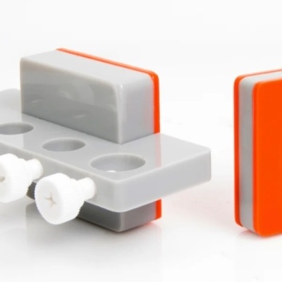 Dois blocos de plástico cinza e laranja com parafusos brancos