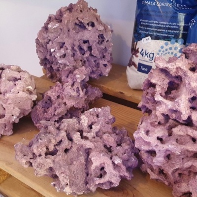 Rochas artificiais cor-de-rosa com textura porosa sobre mesa de madeira e sacos azuis ao fundo